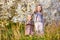 Two little girls in blooming bushes with twigs