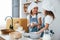 Two little girls in blue chef uniform talking secrets to each other when preparing food on the kitchen