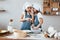 Two little girls in blue chef uniform talking secrets to each other when preparing food on the kitchen