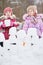 Two little girls build wall from snow blocks