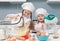 Two little girls in chef uniform with ingredients on table