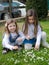 Two little girls collect daisies.