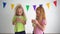 Two Little girls are drinking orange juice from one glass using straw