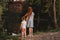 Two little girls enjoy summer in park with scenic placid pond. Sisters holding each other hands. Summer countryside walk