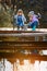 Two little girls with fishing rods, sitting on a wooden pontoon and bragging of caught fish