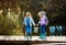 Two little girls with fishing rods, they stand on a wooden pontoon and look at the fish caught in a bucket