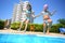 Two little girls holding hands fun jumping into the swimming pool