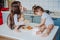 Two little girls in the kitchen sitting on the table.