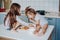 Two little girls in the kitchen sitting on the table.