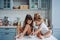 Two little girls in the kitchen sitting on the table.