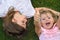 Two little girls laying on the grass, laughing and showing thumbs up