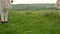 Two little girls are playing on a green meadow. Children`s feet.