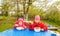 Two little girls, in red jackets, sit at a table and eat pasta.