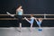 Two little girls repeat the exercises after the teacher on the barre. classes at the choreographic school