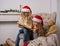 Two little girls in Santa caps are reading a book