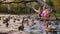 Two little girls sitting by the lake in city park and feeding ducks