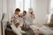 Two little girls in their pajamas are having fun jumping on a bed in a sunlit cozy bedroom