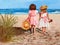 Two little girls walking along the sandy coast of the sea