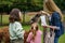 Two little girls and woman feeding fluffy furry alpacas lama. Happy excited children and mother feeds guanaco in a