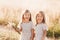 Two little happy identical twin girls playing together in nature in summer. Girls friendship and youth concept. Active children`s