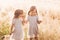 Two little happy identical twin girls playing together in nature in summer. Girls friendship and youth concept. Active children`s