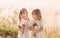 Two little happy identical twin girls playing together in nature in summer. Girls friendship and youth concept. Active children`s