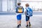 Two little kid boys with backpack or satchel. Schoolkids on the way to school. Healthy adorable children, brothers and