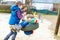 Two little kid boys having fun with chain swing on outdoor playground