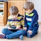 Two little kid boys reading a book at home. Older schoolboy reading for his brother, preschool sibling a fairytale or