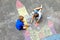 Two little kids boys drawing knight castle with colorful chalks on asphalt. Happy siblings and friends having fun with