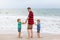 Two little kids boys and father on the beach of ocean