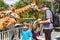 Two little kids boys and father watching and feeding giraffe in