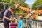 Two little kids boys and father watching and feeding giraffe in zoo. Happy children, family having fun with animals