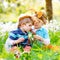 Two little kids boys and friends in Easter bunny ears during traditional egg hunt in spring garden, outdoors. Siblings