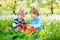 Two little kids boys and friends in Easter bunny ears during traditional egg hunt in spring garden, outdoors. Siblings