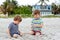 Two little kids boys having fun with building sand castle on tropical beach