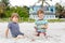 Two little kids boys having fun with building sand castle on tropical beach