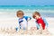 Two little kids boys having fun with building a sand castle on tropical beach of carribean island. children playing