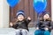 Two little kids boys playing with blue air balloons outdoors. Happy twins and toddler brothers smiling and laughing