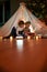 Two little kids, brother and sister reading stories together while sitting on a blanket in a teepee made with bedsheets