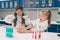 Two little kids in lab coat learning chemistry in school laboratory. Young scientists in protective glasses making