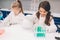 Two little kids in lab coat learning chemistry in school laboratory. Young scientists in protective glasses making