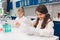 Two little kids in lab coat learning chemistry in school laboratory. Young scientists in protective glasses making