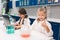 Two little kids in lab coat learning chemistry in school laboratory. Young scientists in protective glasses making