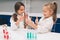 Two little kids in lab coat learning chemistry in school laboratory. Young scientists in protective glasses making