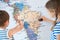 Two little kids in striped shirt measuring with tape world map during geography education