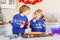 Two little preschool boys baking gingerbread cookies. Happy siblings, children in xmas sweaters. Kitchen decorated for