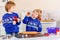 Two little preschool boys baking gingerbread cookies. Happy siblings, children in xmas sweaters. Kitchen decorated for