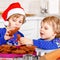 Two little preschool boys baking gingerbread cookies. Happy siblings, children in xmas sweaters. Kitchen decorated for
