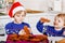 Two little preschool boys baking gingerbread cookies. Happy siblings, children in xmas sweaters. Kitchen decorated for Christmas.